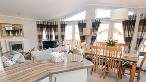 Ein modernes Wohnzimmer mit Sofa, Fernseher und Essbereich mit Holzkohle-Stühlen und einem Tisch.