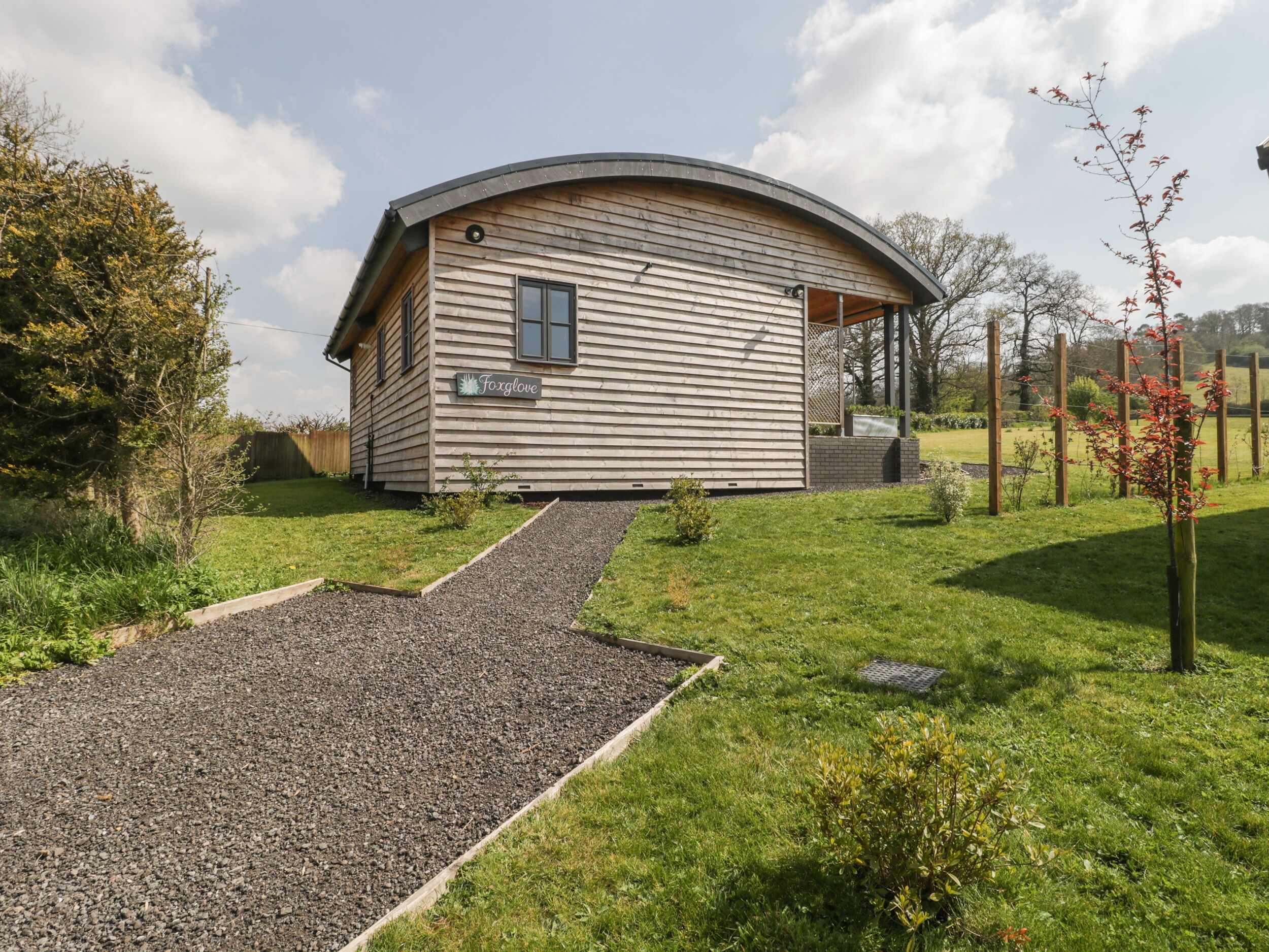 A single-story building with a curved roof, a gravel driveway, and a small garden area.
