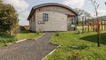 A single-story building with a curved roof, a gravel driveway, and a small garden area.