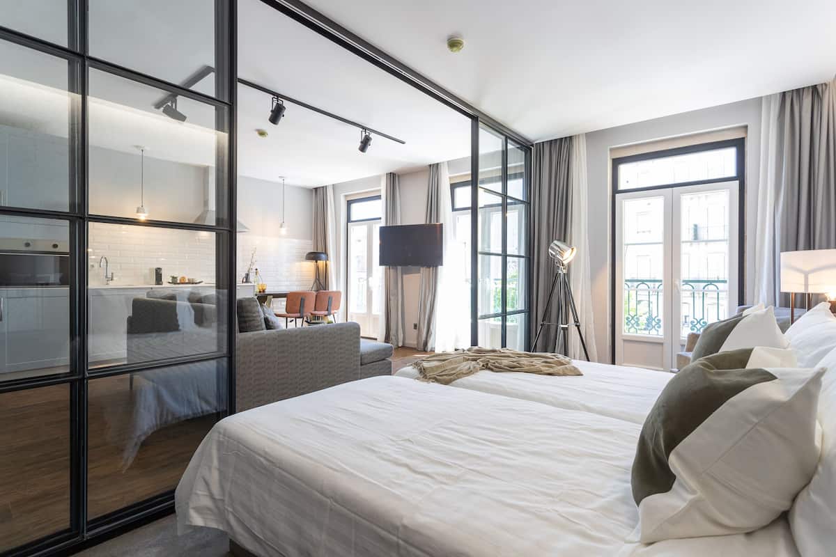 Quarto de hotel moderno com uma cama grande, uma mesa, uma cadeira e uma televisão.