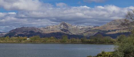 A lake with mountains in the background and a cloudy sky.