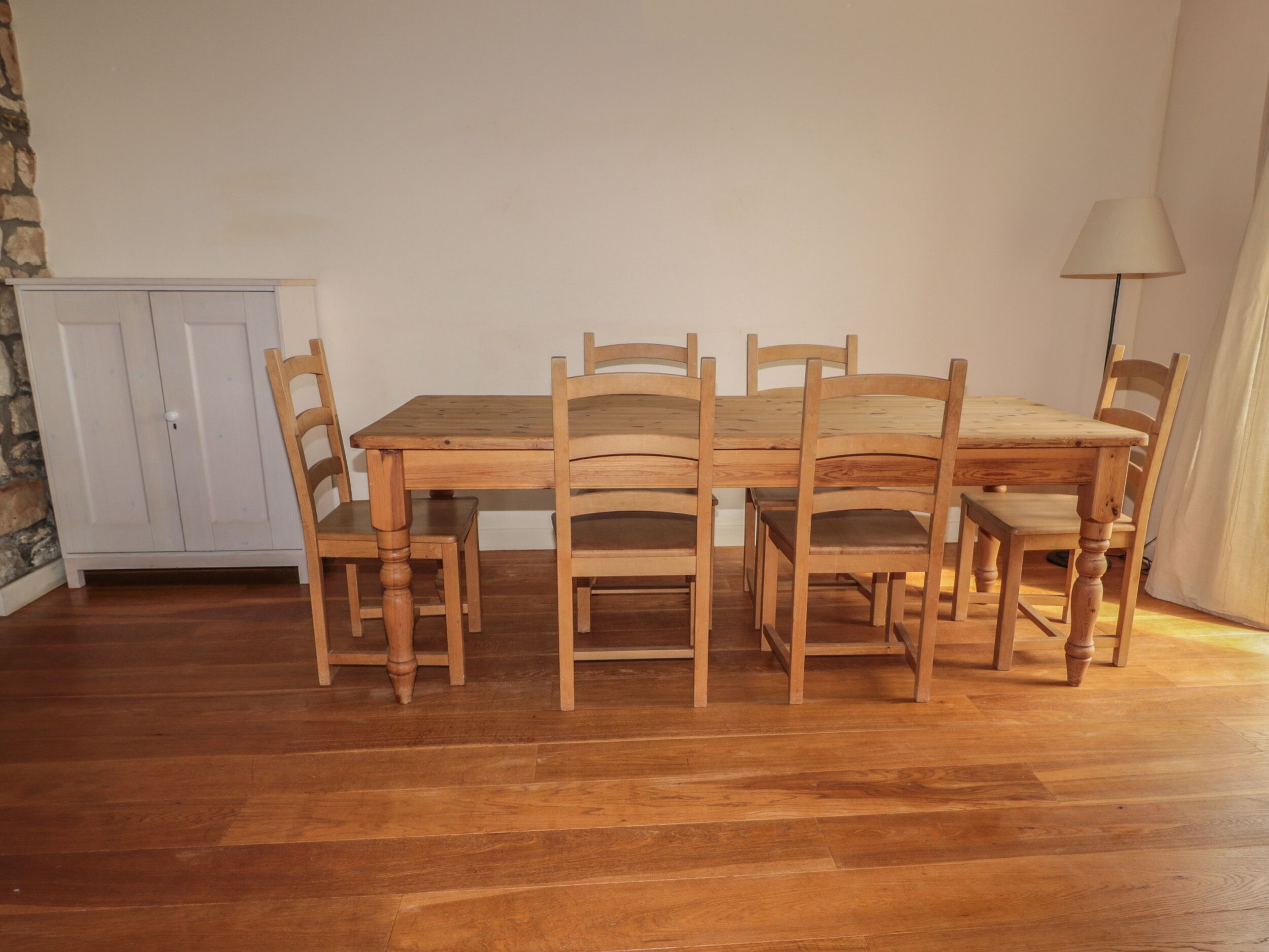 Un coin repas avec une table et des chaises en bois, un buffet blanc et une lampe.