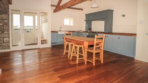 Une cuisine spacieuse avec un plancher en bois, une table à manger et des meubles de rangement bleus.