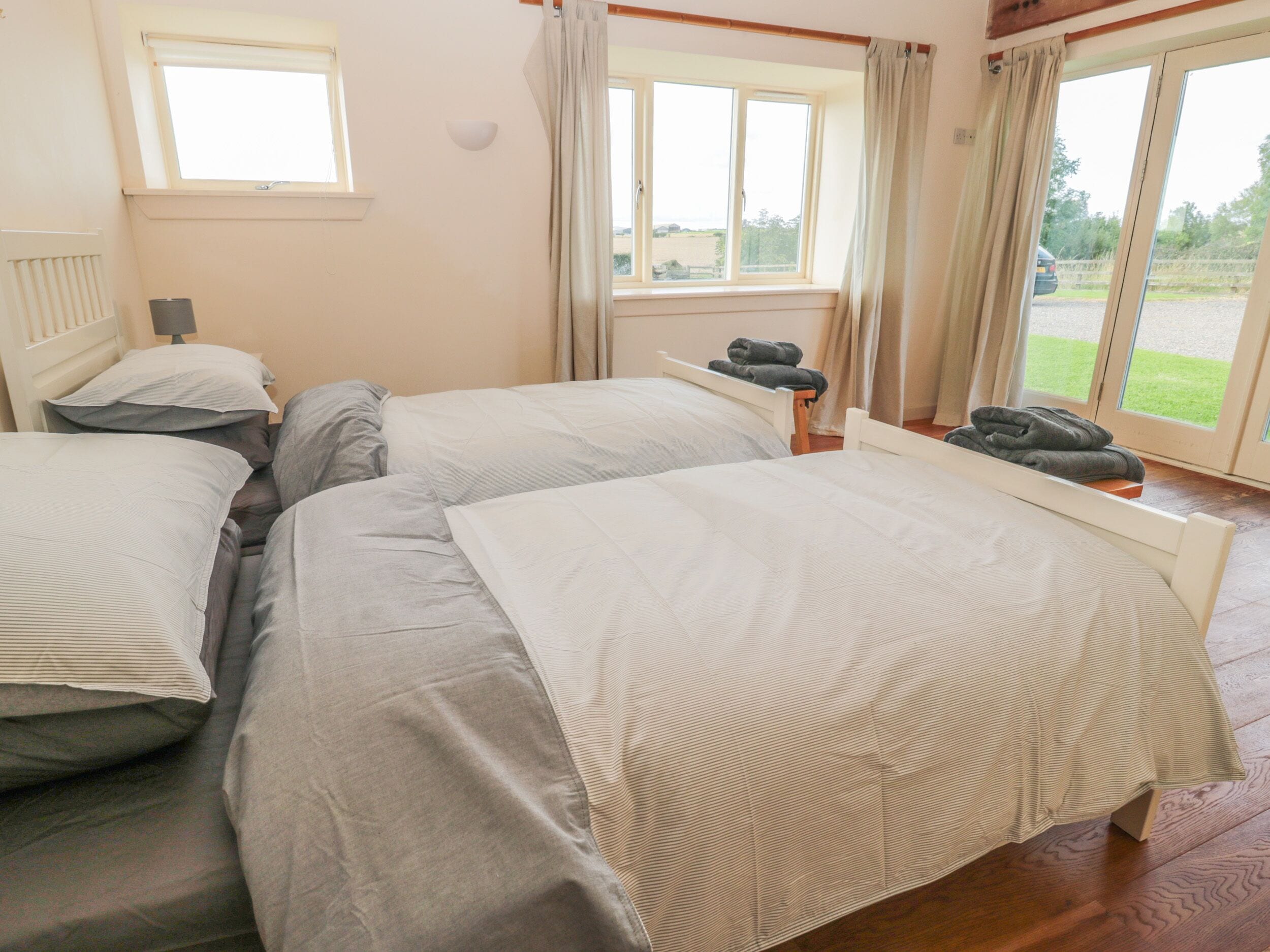A room with two beds, a window, and a view of the outdoors.