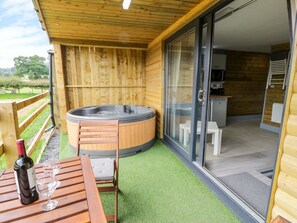 Eine Holzdiele mit Whirlpool, einem Tisch mit einer Weinflasche und einem Glas, und eine Glastür, die zu einer Küchenzeile führt.