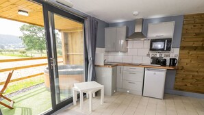 A modern kitchen with a view of a hot tub and a wooden deck. - Cilan Lodge (Corwen)