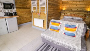 A compact room with a bed, a small kitchenette, and wooden walls. - Cilan Lodge (Corwen)