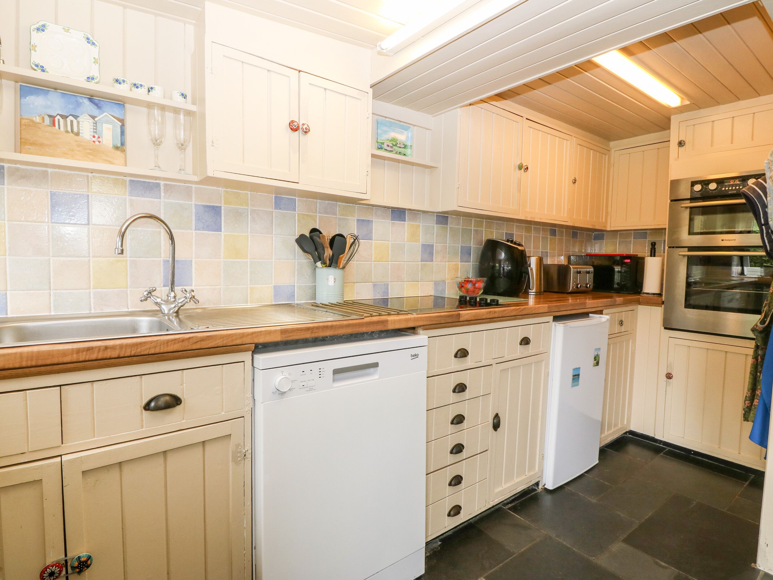 A kitchen with white cabinets, a dishwasher, a coffee maker, and a microwave.