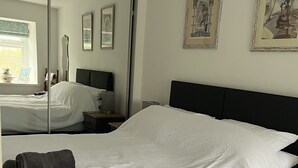 Quarto de hotel com uma cama grande, uma mesa de cabeceira, um espelho e obras de arte na parede.