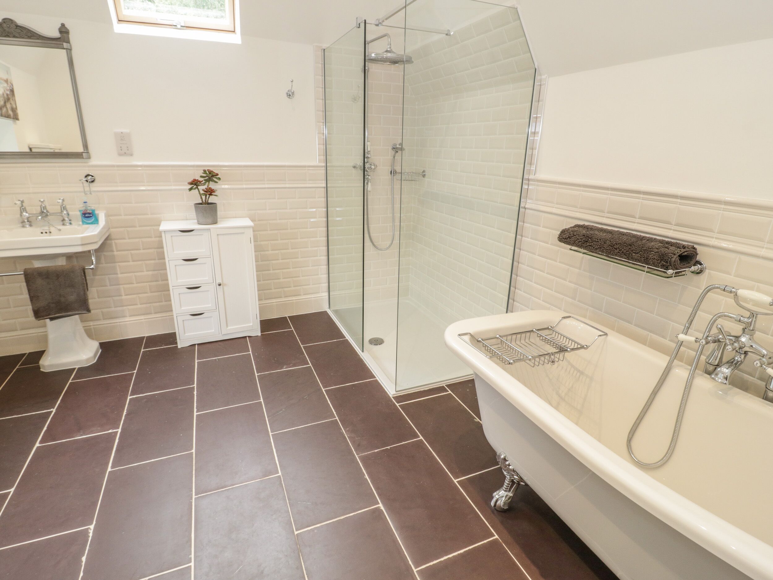 A modern bathroom with a glass-enclosed shower, a freestanding bathtub, and a white vanity with drawers.