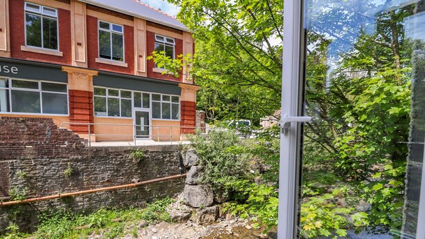 A building with a brick facade, large windows, and a stone wall. - River Cottage (Port Talbot)