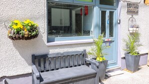 A building with a blue window, a bench, and potted plants. - River Cottage (Port Talbot)
