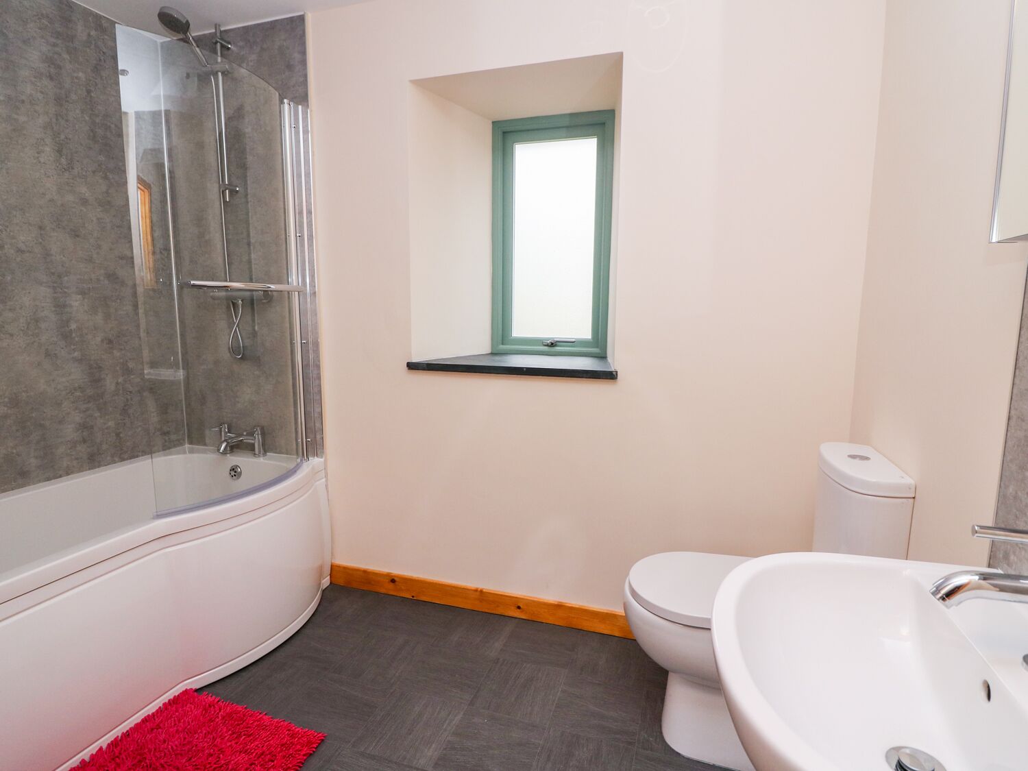 A modern bathroom with a glass-enclosed shower, a white bathtub, a white toilet, and a white sink.