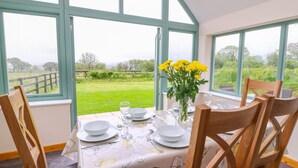Comedor con una mesa lista para cuatro, ventanas amplias y vistas a un paisaje verde.