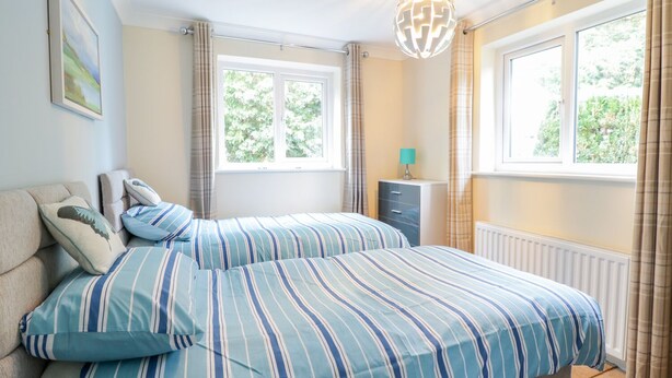 A bedroom with a bed, a dresser, a lamp, and a globe light. - Tanglewood (Colwyn Bay)