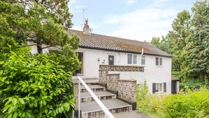 A two-story house with a tiled roof, a small front garden, and a number '15' sign on the steps. - Tanglewood (Colwyn Bay)