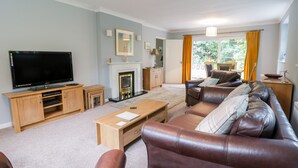 A living room with a television, sofa, coffee table, fireplace, and a view of the outdoors. - Tanglewood (Colwyn Bay)
