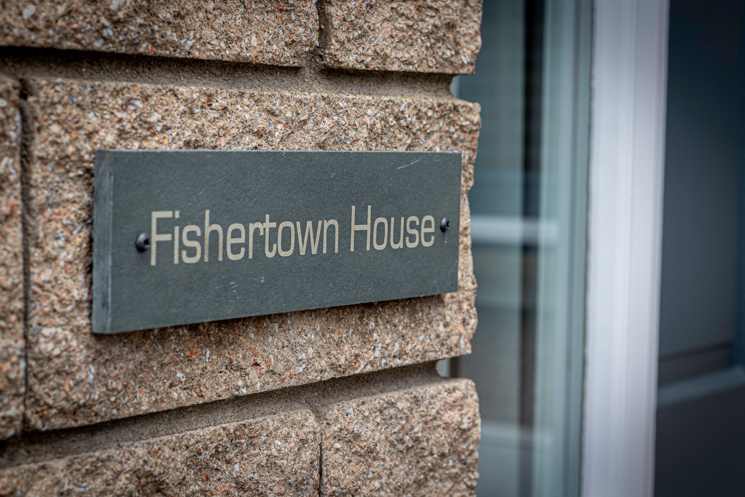 Een stenen muur met een bord waarop staat 'Fishertown House'.