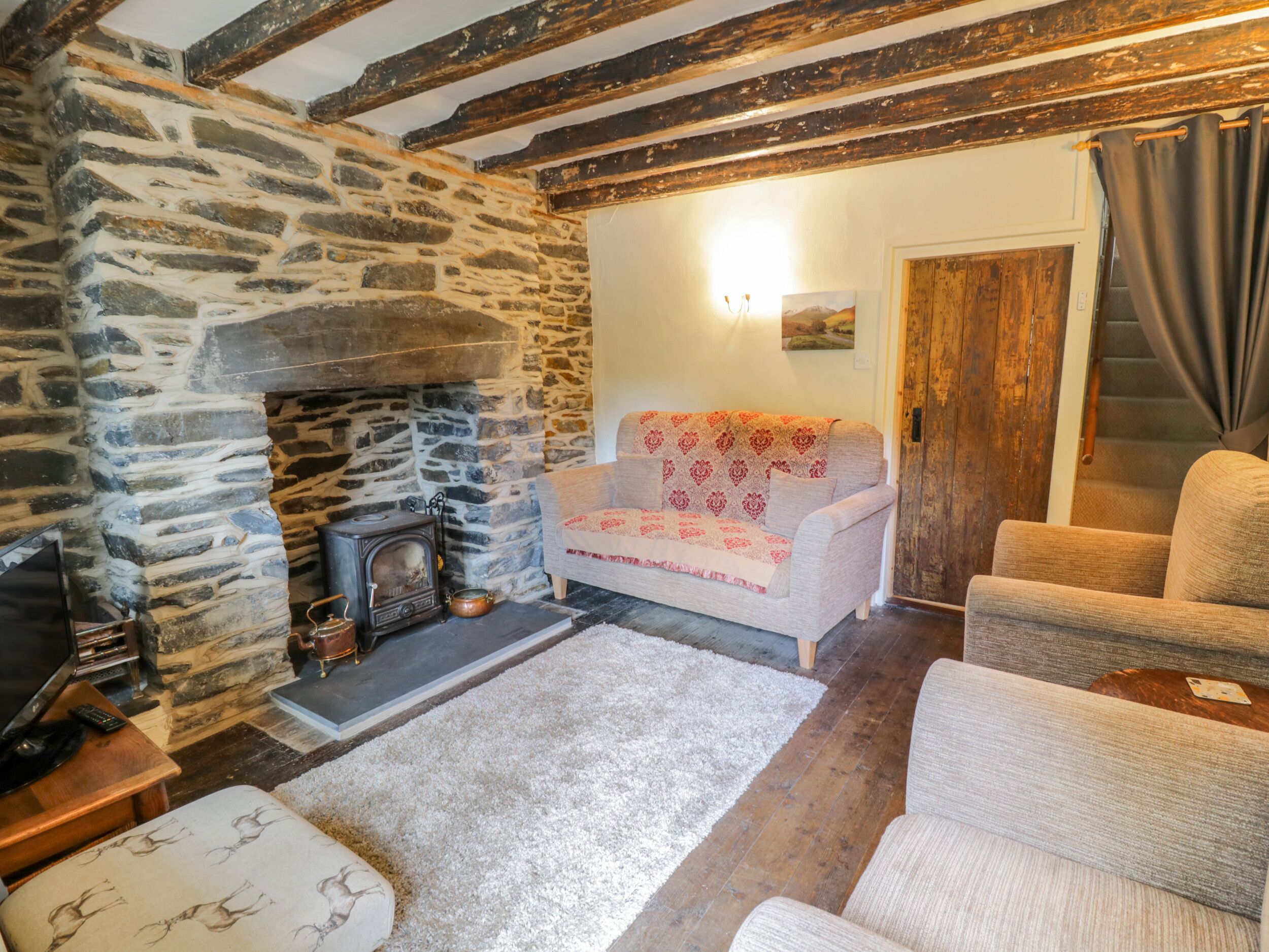 A cozy living room with a stone fireplace, a sofa, and a television.