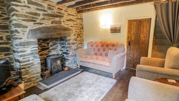 A cozy living room with a stone fireplace, a sofa, and a television.
