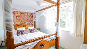 A four-poster canopy bed with a colorful headboard, a wooden frame, and a white canopy. - Dyfi Cottage (Machynlleth)