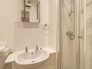 A bathroom with a white sink, two faucets, a mirror, and a glass-enclosed shower. - Hillcrest (Scarborough)