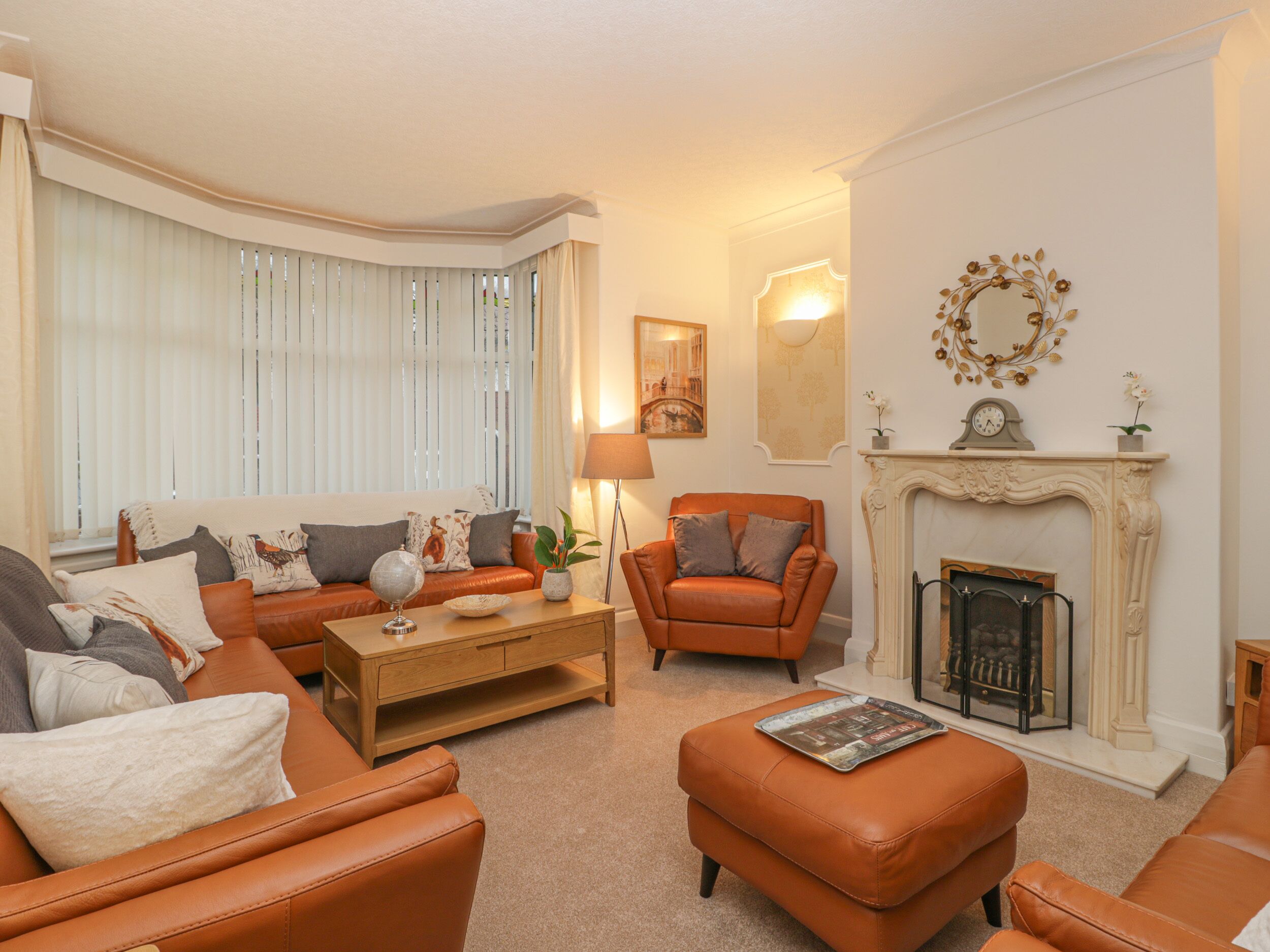 A living room with a fireplace, leather sofas, a coffee table, and a fireplace mantle with a clock and decorative items.