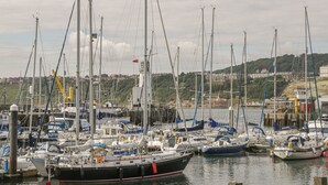 A marina with multiple boats docked, surrounded by a hilly landscape and buildings in the background. - Hillcrest (Scarborough)