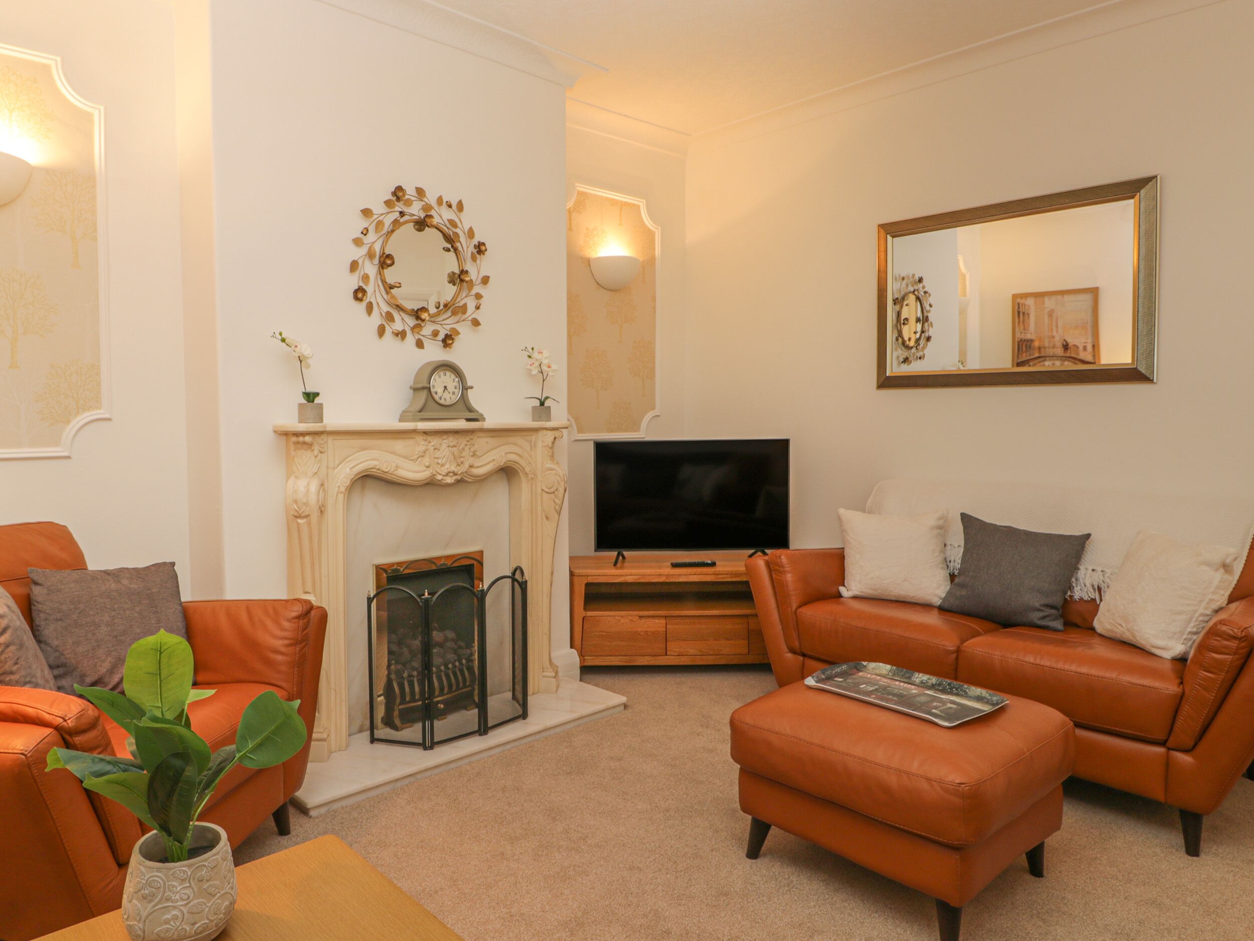 A living room with a fireplace, a television, and two leather sofas.