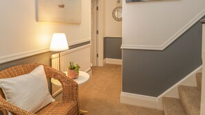 A cozy room with a wicker chair, a small table with a lamp, and a potted plant. - Hillcrest (Scarborough)