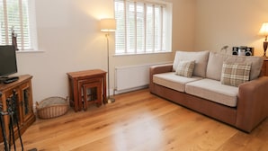 A cozy living room with a sofa, a television, a lamp, and a radiator. - Wyke Lodge Cottage (Scarborough)