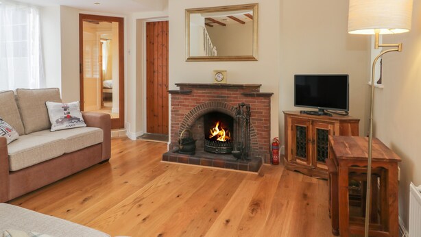 A living room with a fireplace, wooden beams on the ceiling, a television, and a sofa. - Wyke Lodge Cottage (Scarborough)