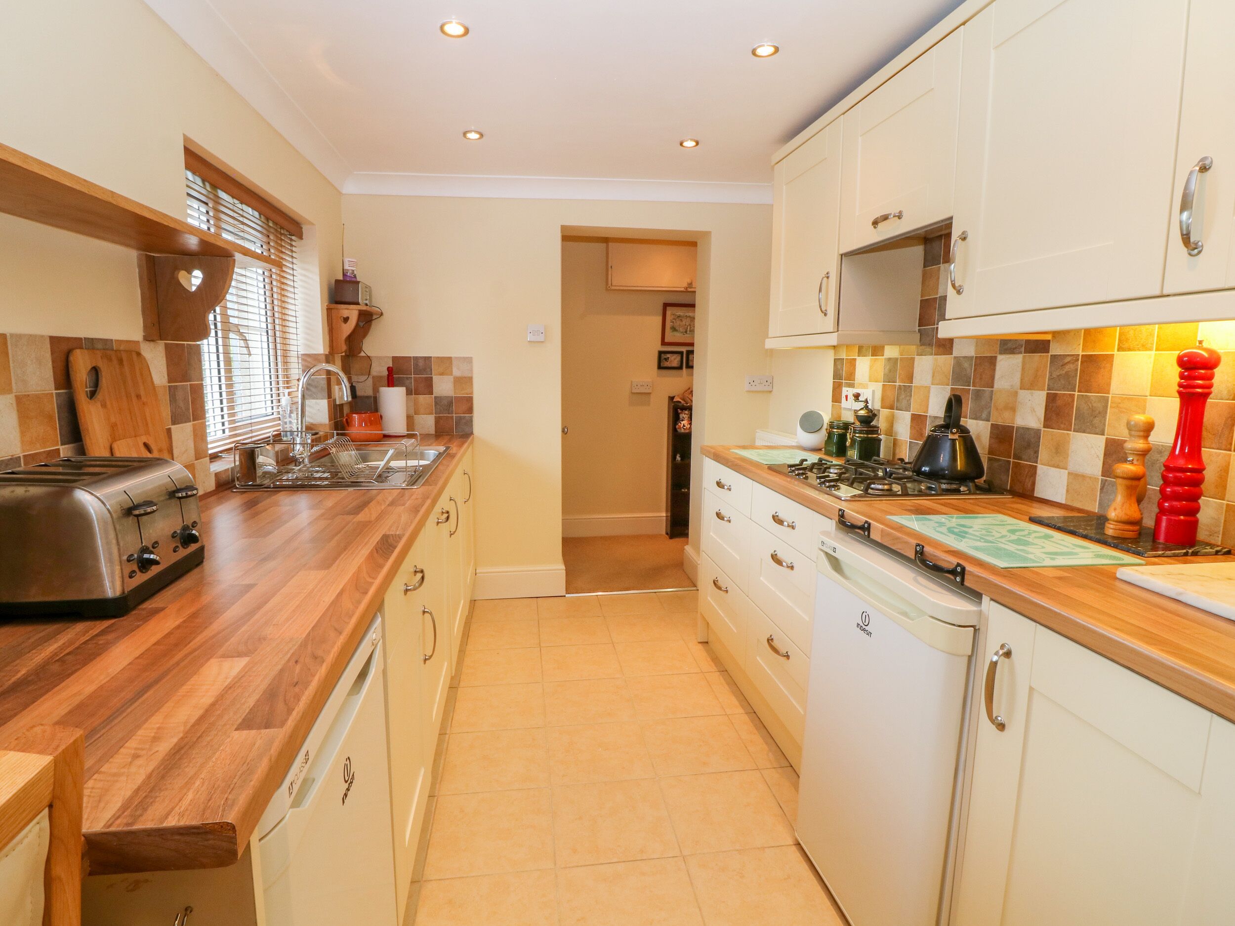 A compact kitchen with a toaster, sink, stove, and wooden cabinets.