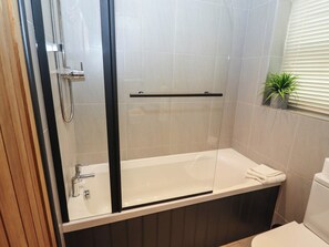 Un bagno moderno con doccia vetrata, una vasca da bagno bianca e un water.