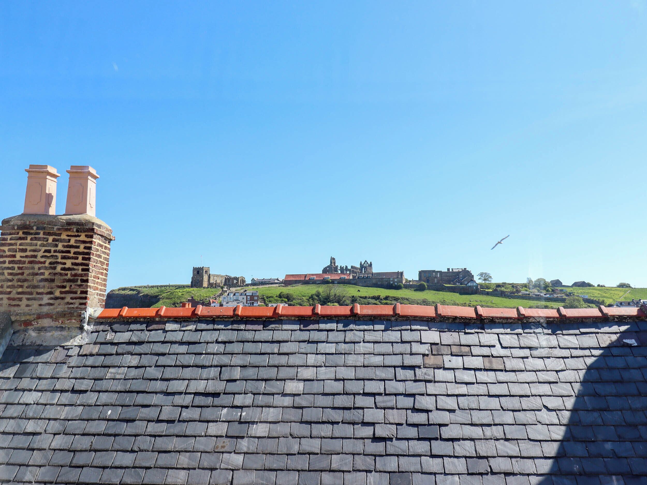A brick building with a red-tiled roof and a chimney.