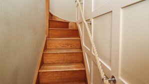 A wooden staircase with a rope barrier, white walls, and a framed picture on the wall. - Gavel Cottage (Whitby)
