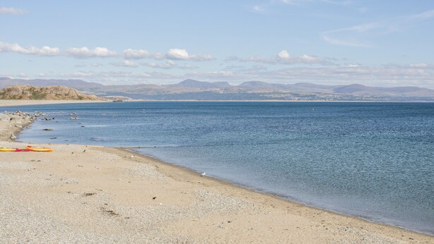 Une plage offrant une vue dégagée sur la mer et les montagnes lointaines.