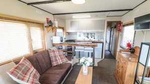 A compact living space with a sofa, a small table, and a kitchenette. - Castle View Cabin (Scarborough)