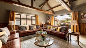 A spacious living room with a large sectional sofa, a glass coffee table, and a fireplace. - Sykes Lodge (Malton)
