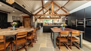 A spacious kitchen with wooden beams, a central island, and modern appliances. - Sykes Lodge (Malton)