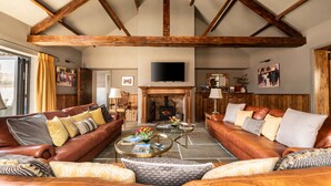 A spacious living room with leather sofas, a fireplace, and a television mounted on the wall. - Sykes Lodge (Malton)