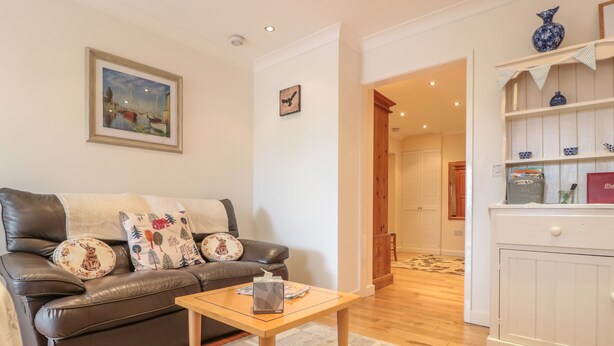 Una sala de estar con un sofá de cuero marrón, una mesa de centro de madera y un mueble blanco con objetos decorativos.