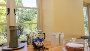 A kitchen with a wooden countertop, a kettle, a teapot, a pitcher, and two containers labeled "coffee" and "tea". - Pheasant Cottage (Bath)