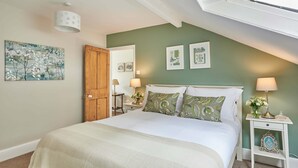 A bedroom with a bed, a nightstand, a lamp, a door, and wall art.