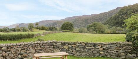 A stone wall with a picnic table in a grassy field.