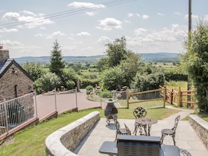 Eine Terrasse mit Gartenmöbeln, einem Grill und einer Steinmauer.