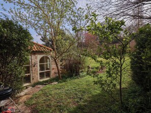 Enjoy a, serene space surrounded by lush greenery and a barbecue grill for outdoor dining.