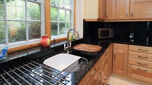 Une cuisine avec une fenêtre, un évier, un four à micro-ondes et des armoires en bois.