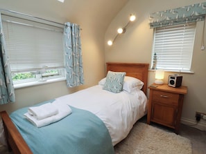 Un dormitorio con cama, mesita de noche, lámpara y radio.