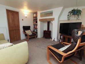 A living room with a sofa, two armchairs, a bookshelf, a television, and a fireplace.